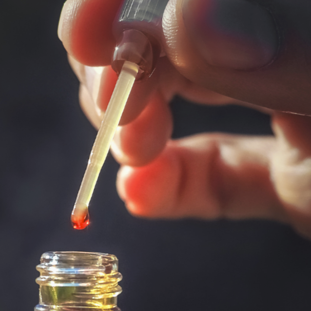 Person applying fragrance oil from bottle using a dipping stick